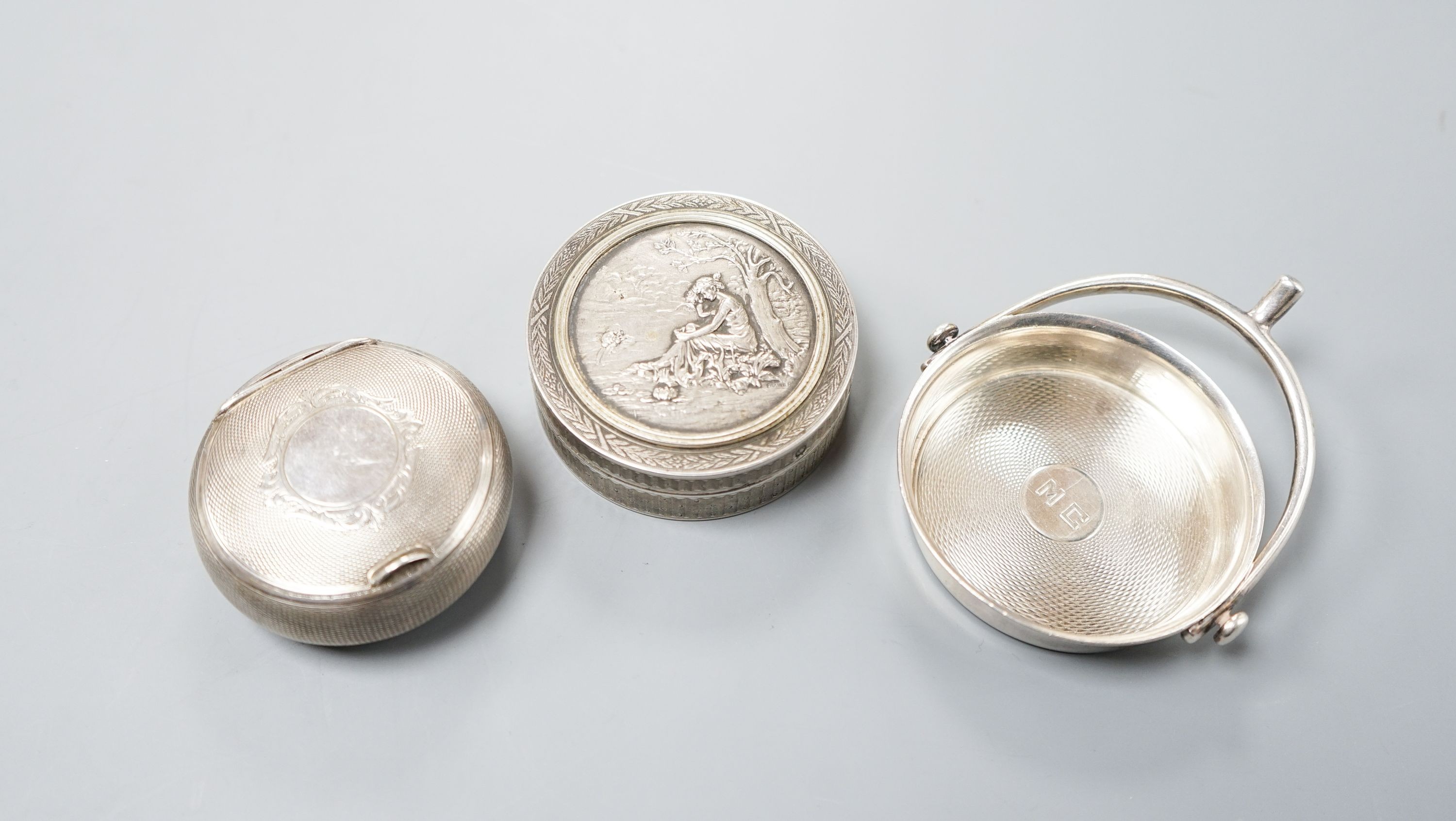 An early 20th century French engine turned white metal compact, 55mm, a similar circular box and embossed cover by Charles Barrier and a similar small dish with stirrup handle by Hermes.